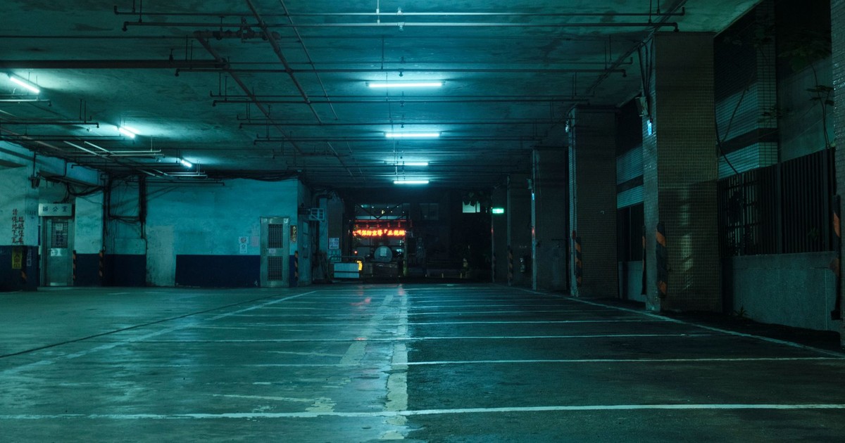 Dimly lit urban parking garage with fluorescent lights creating a moody atmosphere.