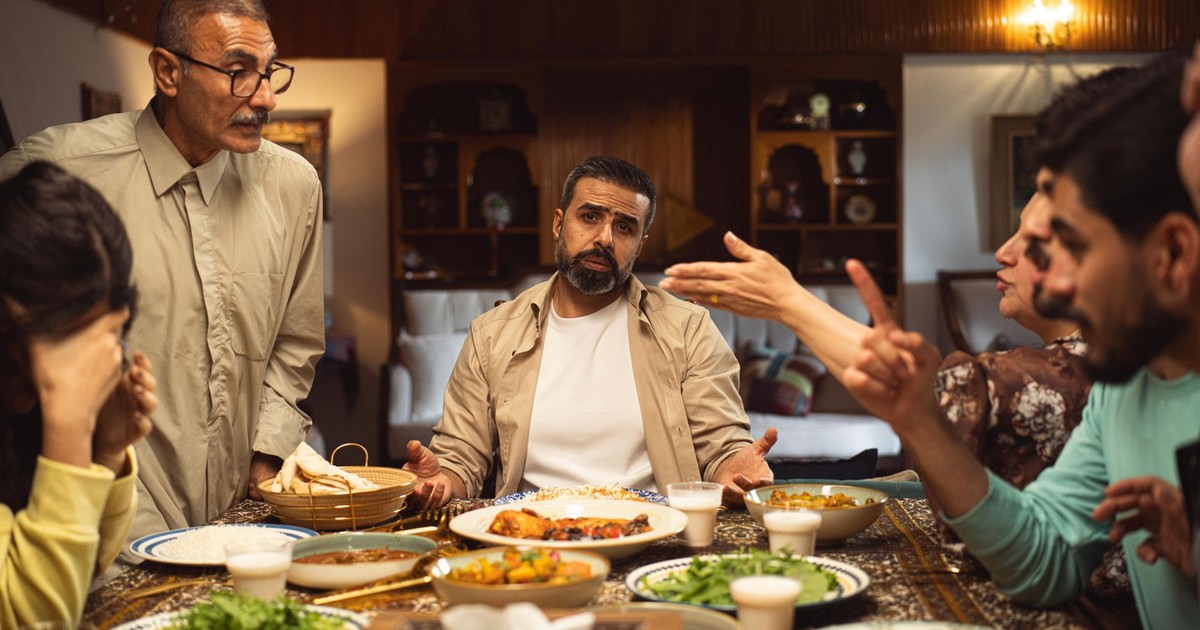 A family engages in a lively discussion around a dinner table filled with dishes.