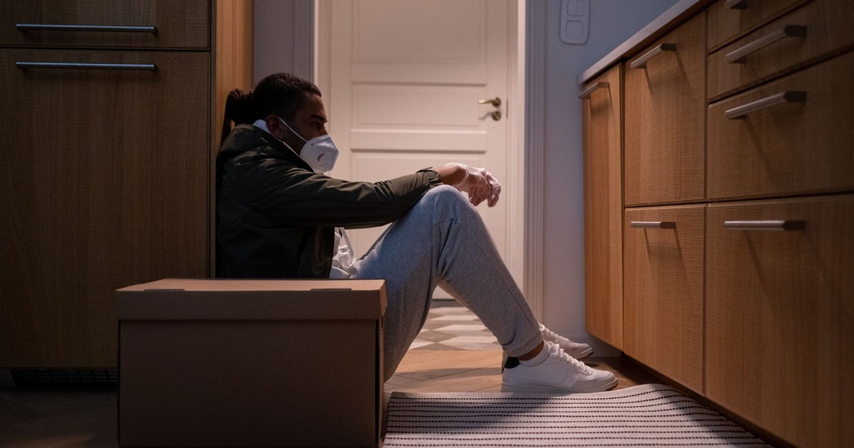 Man wearing a mask sitting on the kitchen floor, reflecting on life changes.