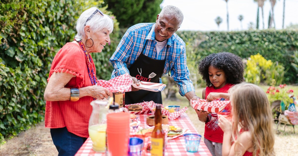A joyful family gathers outdoors for a picnic, enjoying food and togetherness.