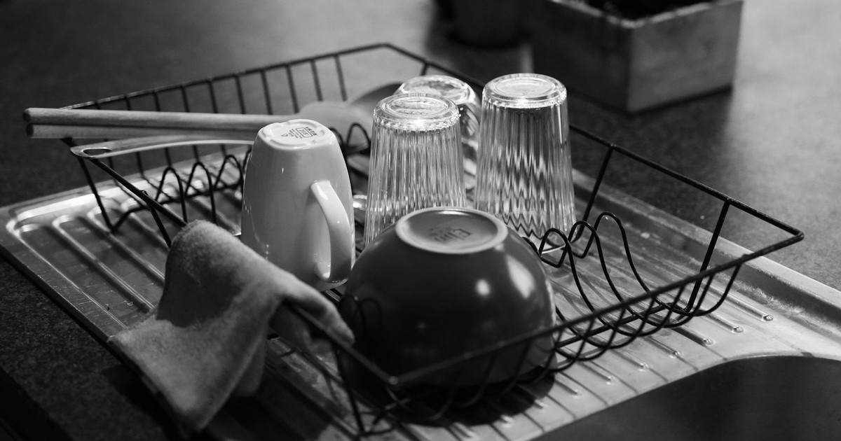 Black and white shot of a dish rack with glass and ceramic kitchenware.