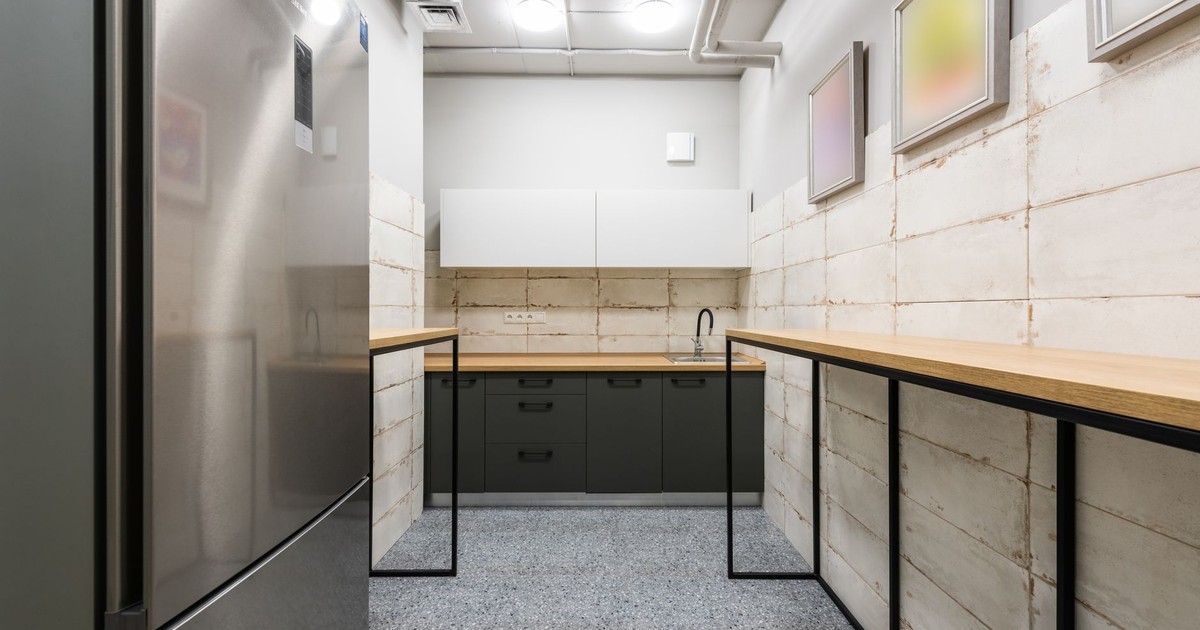 Interior of simple kitchen with new wooden counters and fridge in workplace designed in minimal style