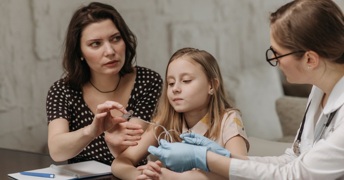 A mother and daughter consult a doctor during a home visit for healthcare advice.