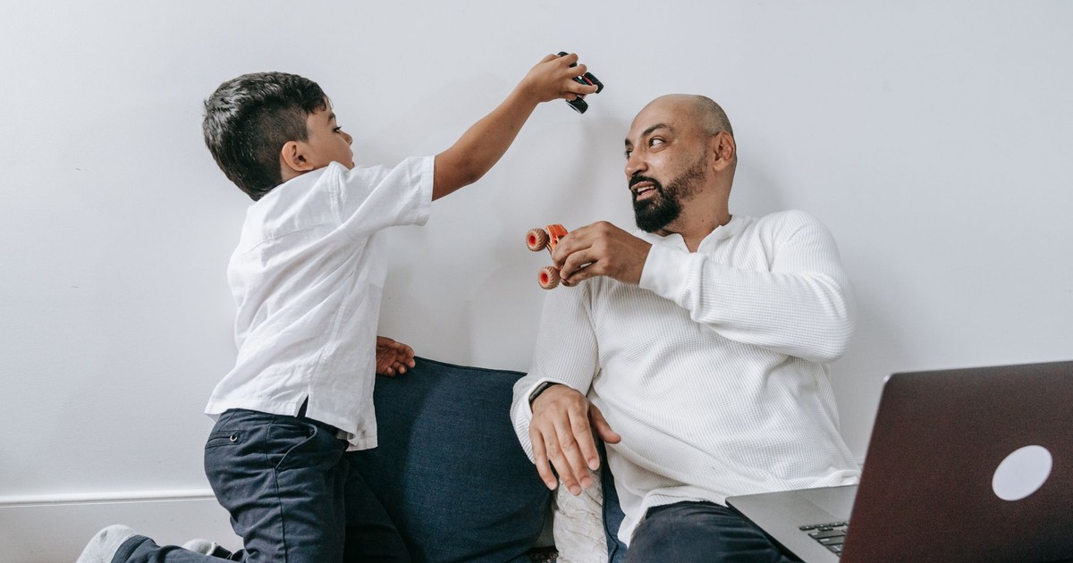 A father and son share a playful moment indoors, enjoying quality bonding time together.