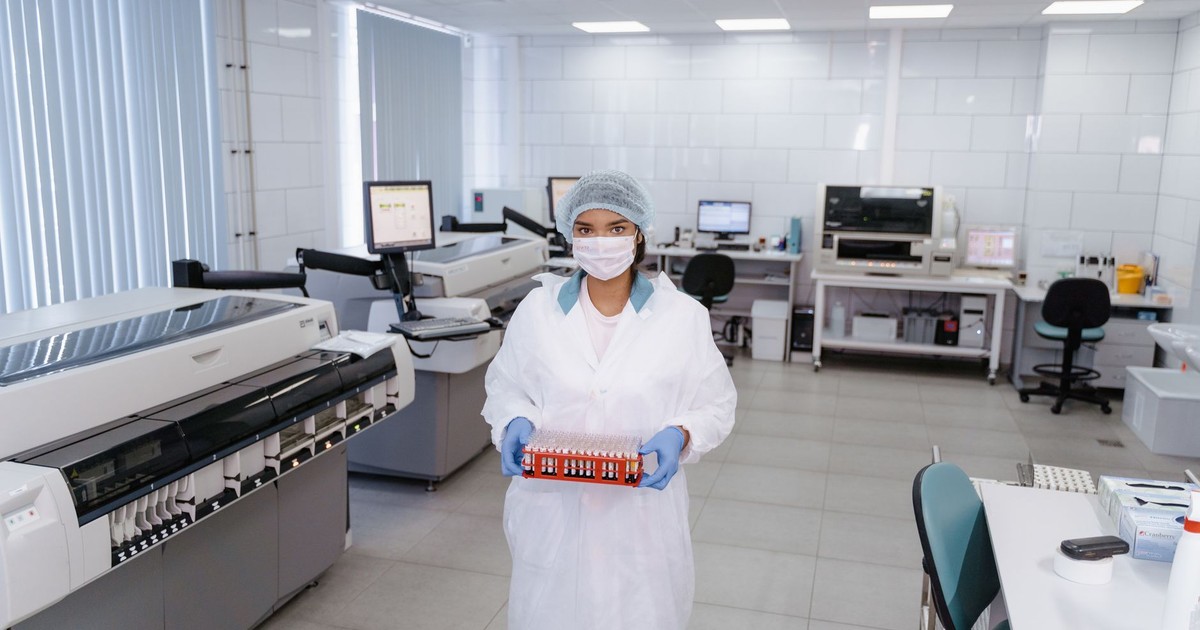 A scientist in protective gear holding test samples in a modern laboratory setting.