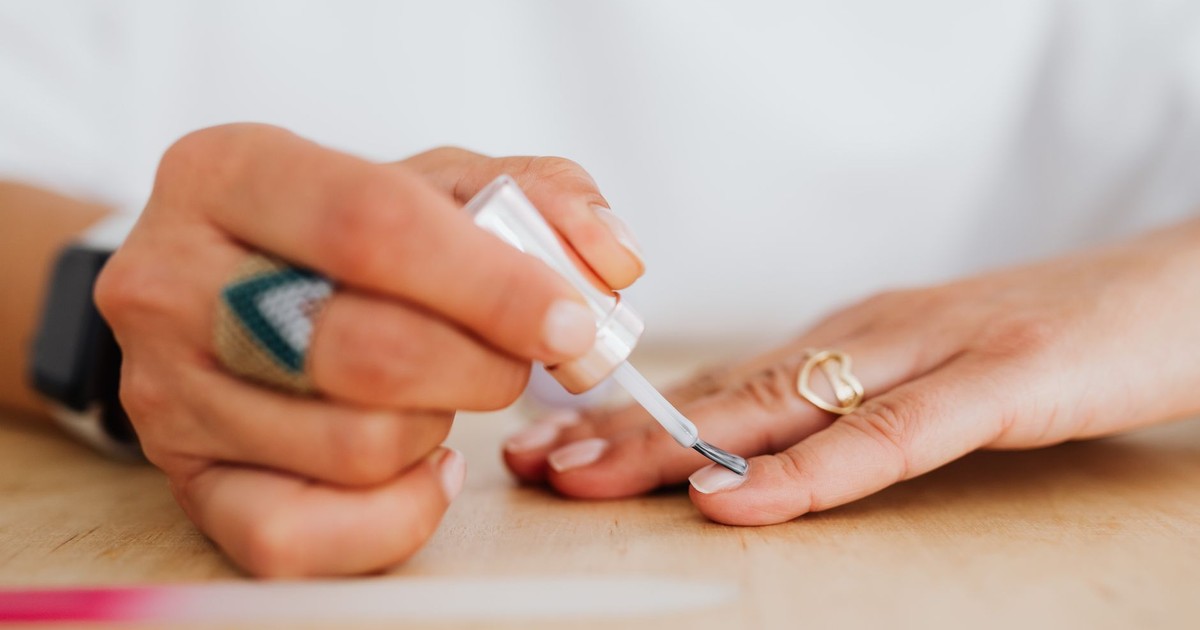 A close-up of a woman applying clear nail polish for a neat manicure.
