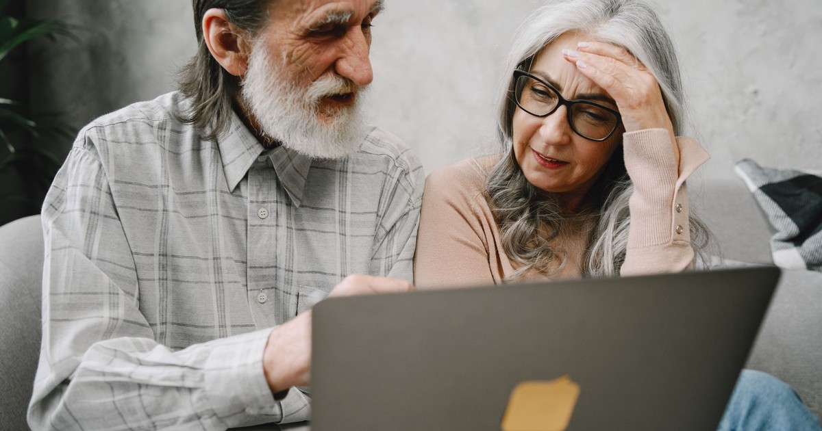 Senior couple using a laptop together at home, engaging in a focused conversation.