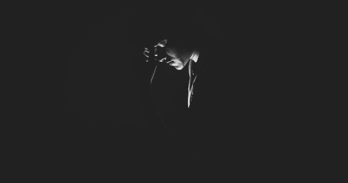 A solitary man is captured in a black and white moody setting, evoking feelings of loneliness and introspection.