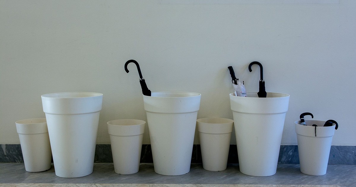 A minimalist display featuring white containers holding black umbrellas, set indoors.