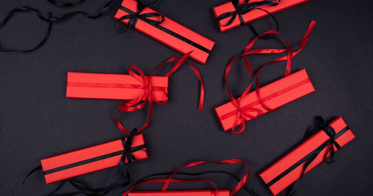 Top view of red and black wrapped gift boxes with ribbons on a black surface, ideal for festive occasions.