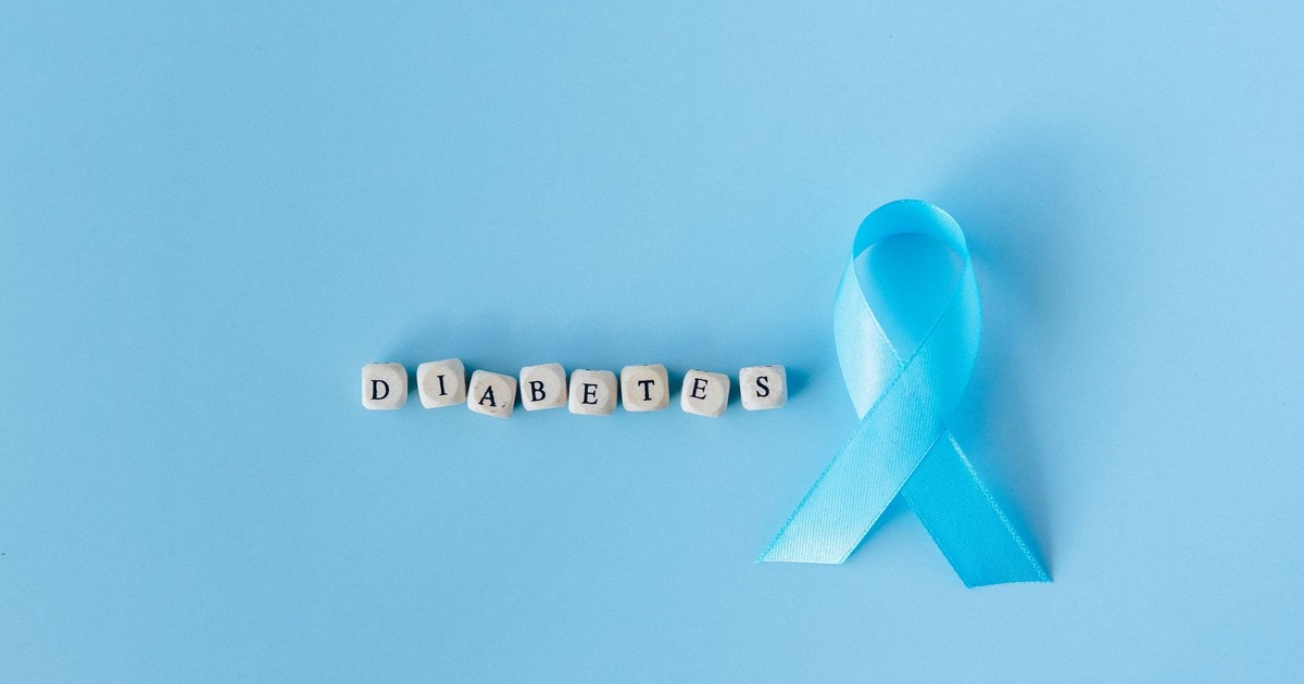 Blue ribbon signifies diabetes awareness on a light blue surface with letter dice spelling 'Diabetes'.