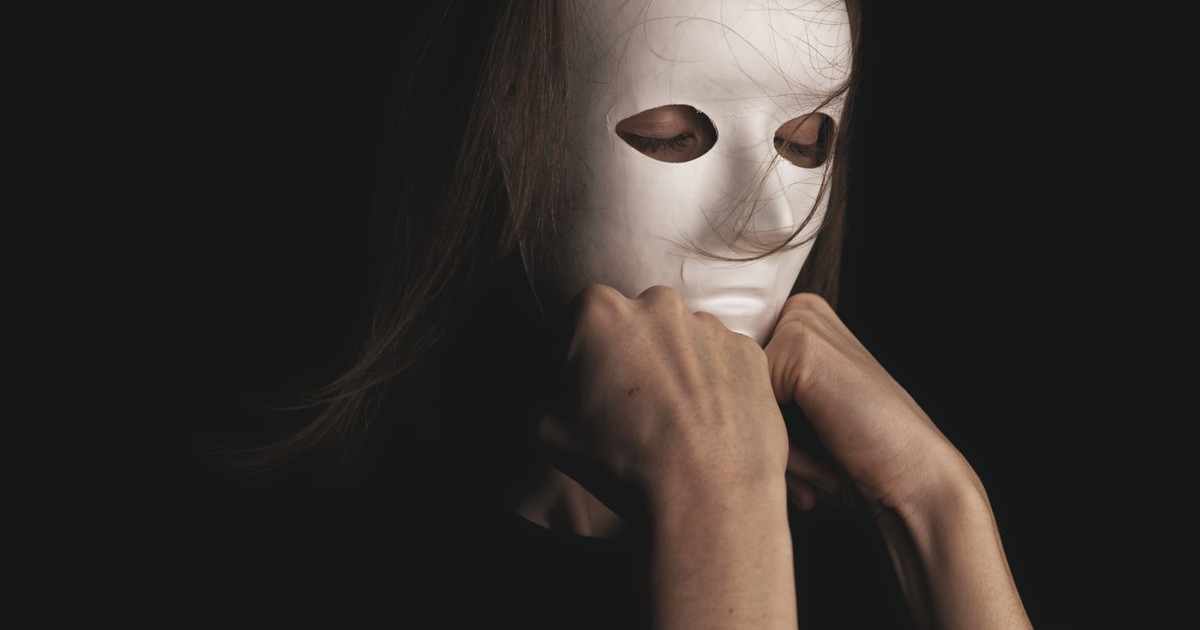 An enigmatic figure wearing a white mask, set against a dim backdrop, evokes mystery.