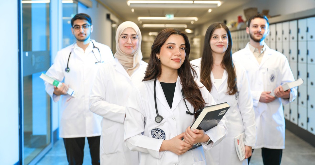 Group of diverse medical students wearing lab coats in university corridor, representing future healthcare professionals.