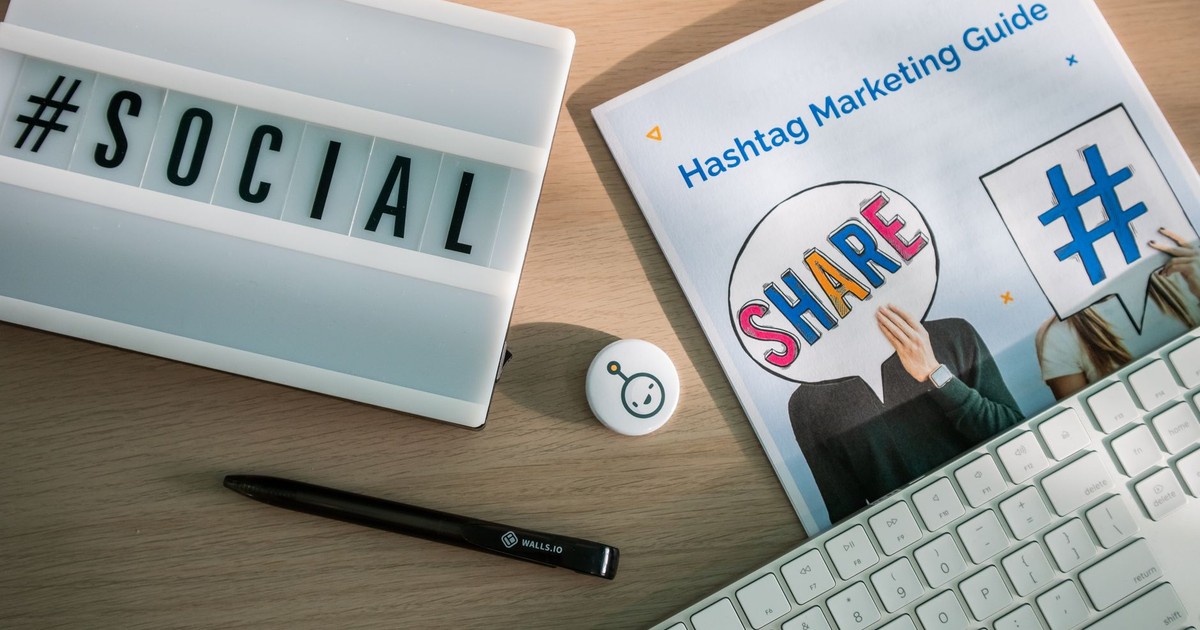 A desktop setup with social media marketing essentials including a keyboard, lightbox, and guide.